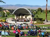 Orchestra playing at Gene Kleiner bandshell while people in lawn chairs listen.
