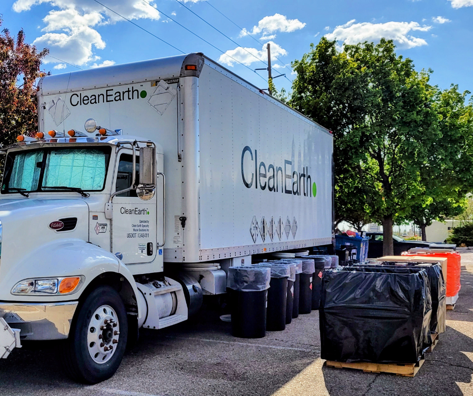 Clean Earth Household Hazardous Waste (HHW) mobile collection truck with various containers on the pavement in front of it for HHW items